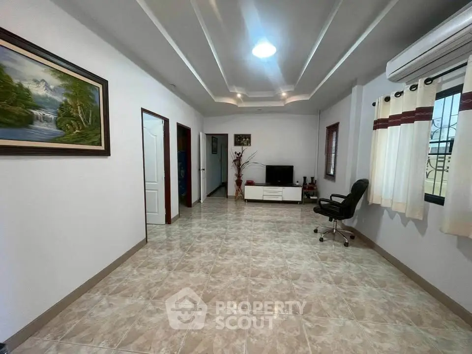 Spacious living room with modern decor and natural light, featuring tiled floors and a cozy seating area.