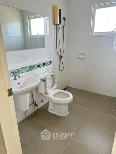 Modern bathroom with sleek fixtures and tiled walls, featuring a shower and window for natural light.