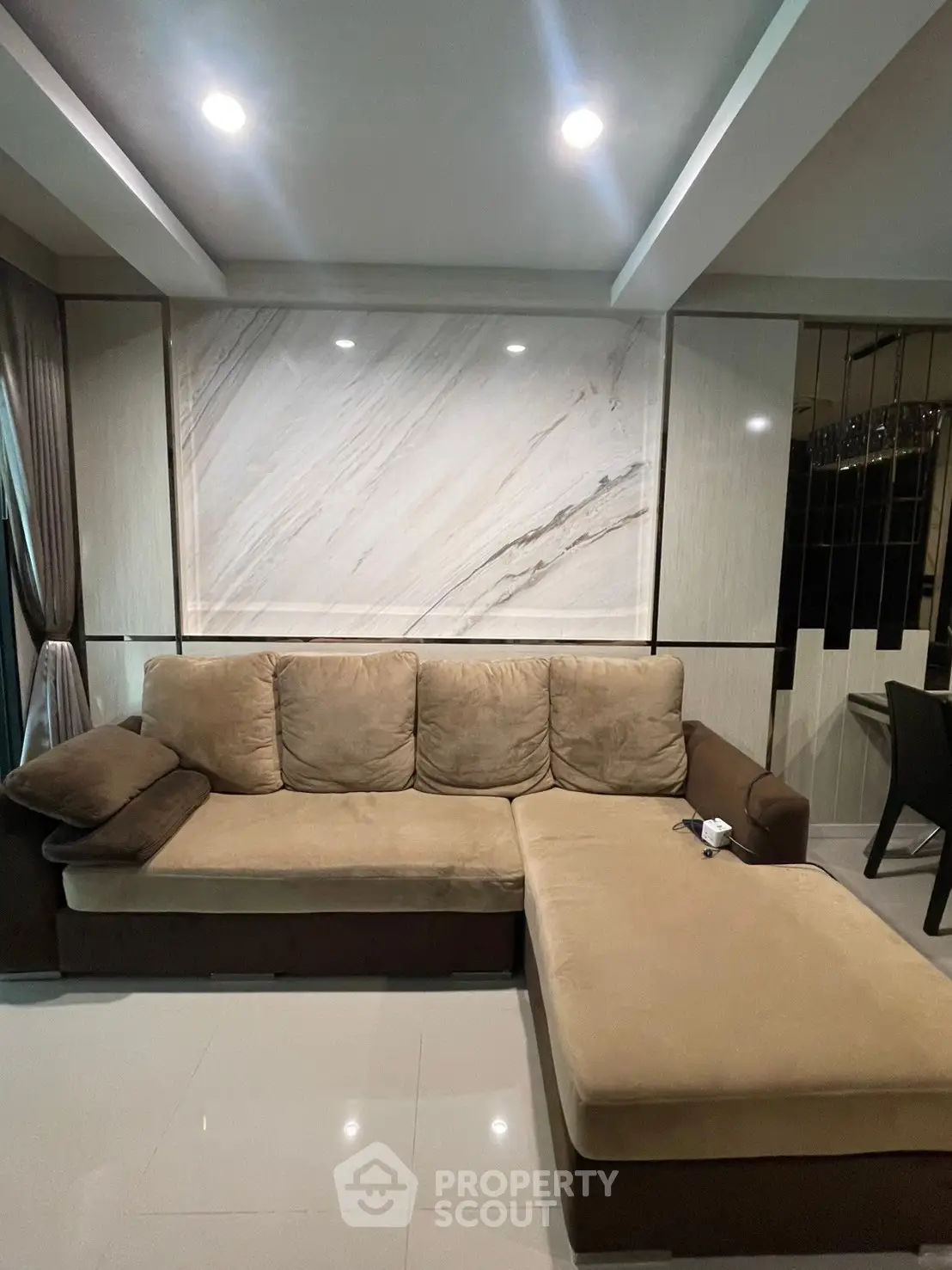 Elegant living room with plush sectional sofa and marble accent wall, perfect for modern comfort and style.