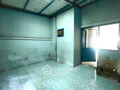 Spacious room with tiled floor and natural light, ideal for renovation.