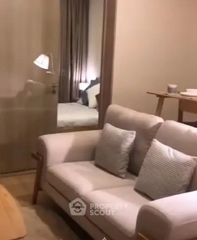 Cozy living room with modern sofa and view into a stylish bedroom