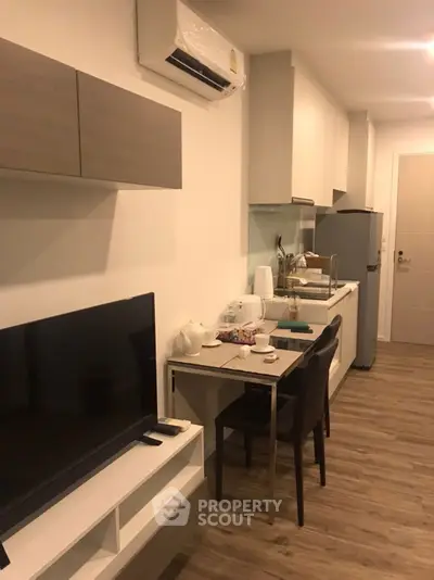 Modern compact kitchen with dining area and sleek appliances in cozy apartment.