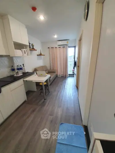 Modern apartment interior with cozy living area and kitchen, featuring sleek wooden flooring and natural light.