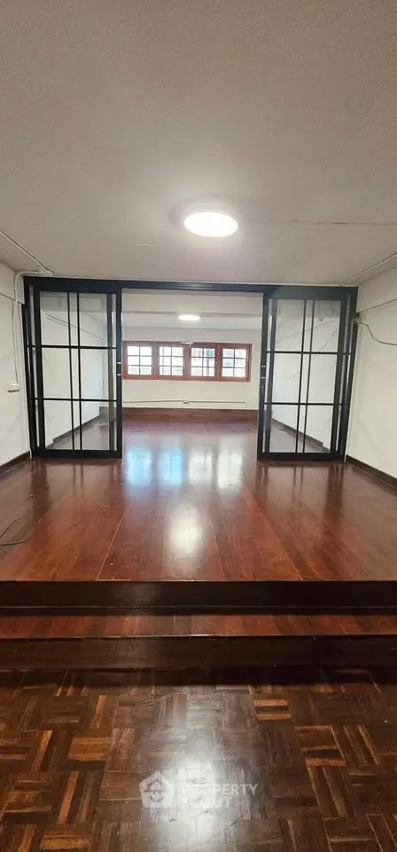 Spacious interior with wooden flooring and large windows, ideal for a modern living room or office space.