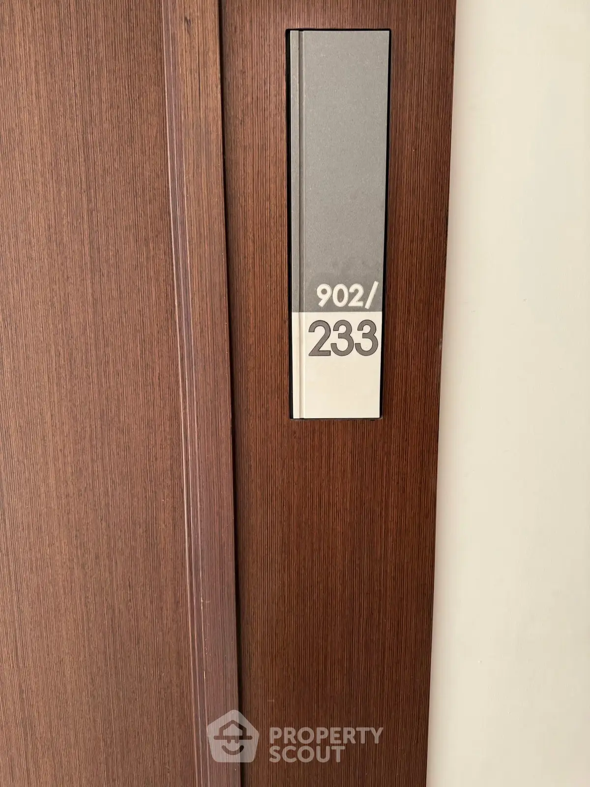 Stylish modern apartment door with sleek wooden finish and room number 902/233.
