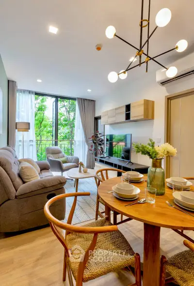 Modern living room with stylish decor and large windows offering a lush green view.