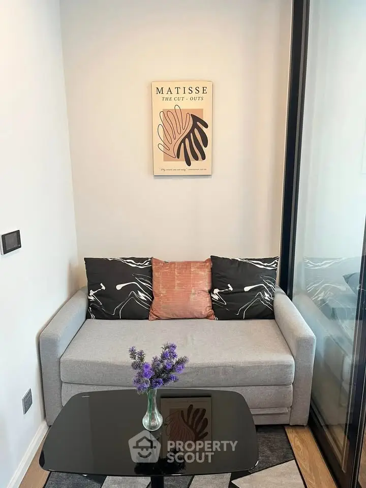 Cozy living room with modern decor, featuring a stylish sofa, glass coffee table, and Matisse artwork on the wall.