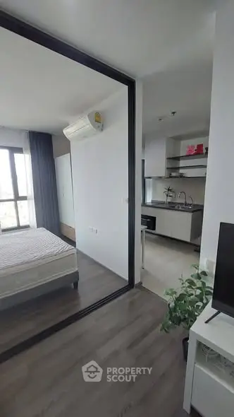Modern apartment interior with bedroom and kitchen, featuring sleek design and natural light.
