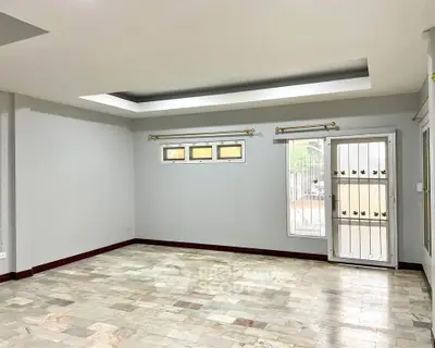 Spacious empty room with tiled floor and large window, perfect for customization.