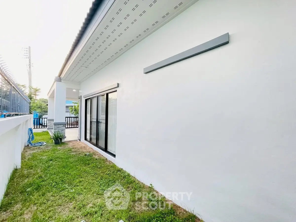 Modern white exterior with sliding glass doors and lush green lawn, perfect for outdoor relaxation.