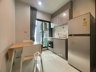 Modern kitchen with sleek cabinetry, dining table, and large fridge in a compact space.