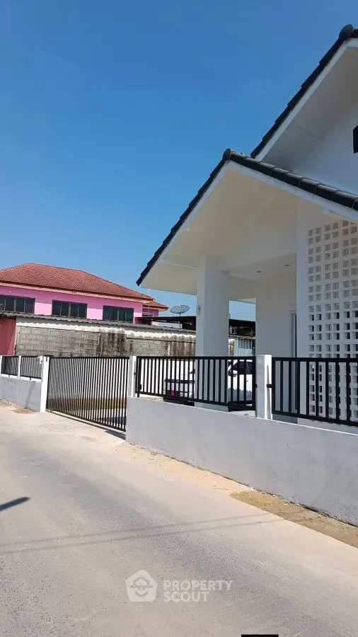 Modern white house exterior with sleek fence and clear blue sky