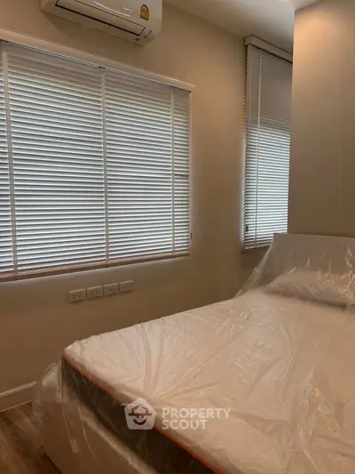 Cozy bedroom with air conditioning and natural light through blinds, perfect for relaxation.