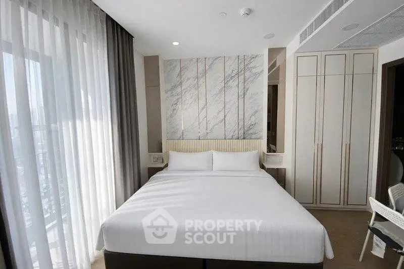 Luxurious bedroom with modern design and large window offering natural light.
