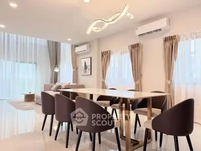 Elegant dining area with modern chandelier and cozy living room in open layout design.