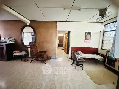 Spacious living room with vintage decor and natural light, featuring a cozy sofa and elegant wooden chair.