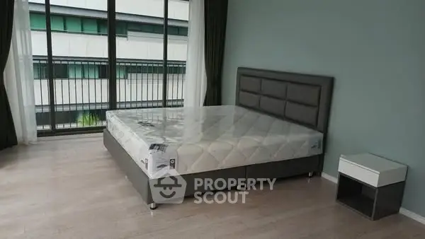 Spacious bedroom with modern bed and large windows offering natural light.