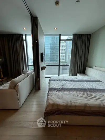 Modern bedroom with city view, featuring large windows and stylish furnishings.
