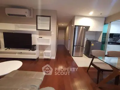 Modern living room with hardwood floors, sleek furniture, and open kitchen layout in a stylish apartment.