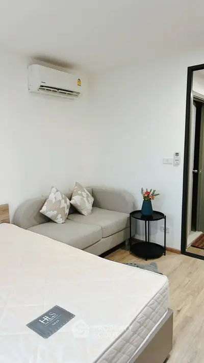 Cozy bedroom with modern decor and air conditioning, featuring a comfortable sofa and stylish side table.