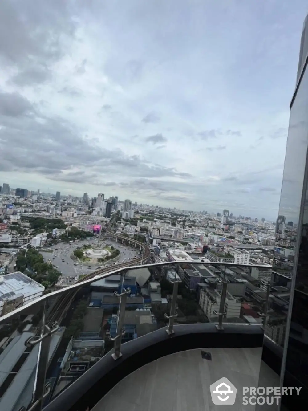 Stunning cityscape view from a high-rise balcony with modern glass railing.