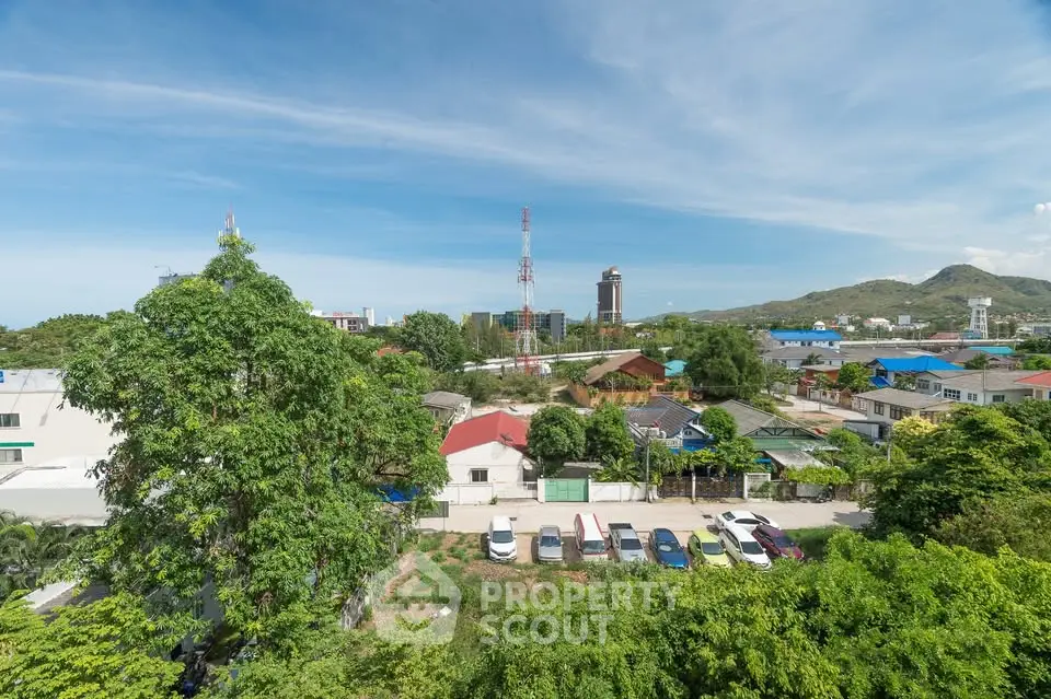 Scenic view of suburban neighborhood with lush greenery and distant hills under a clear blue sky.