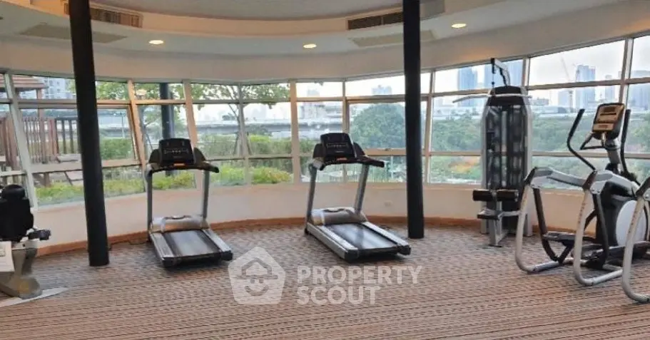 Spacious gym with modern equipment and panoramic city views, ideal for fitness enthusiasts.