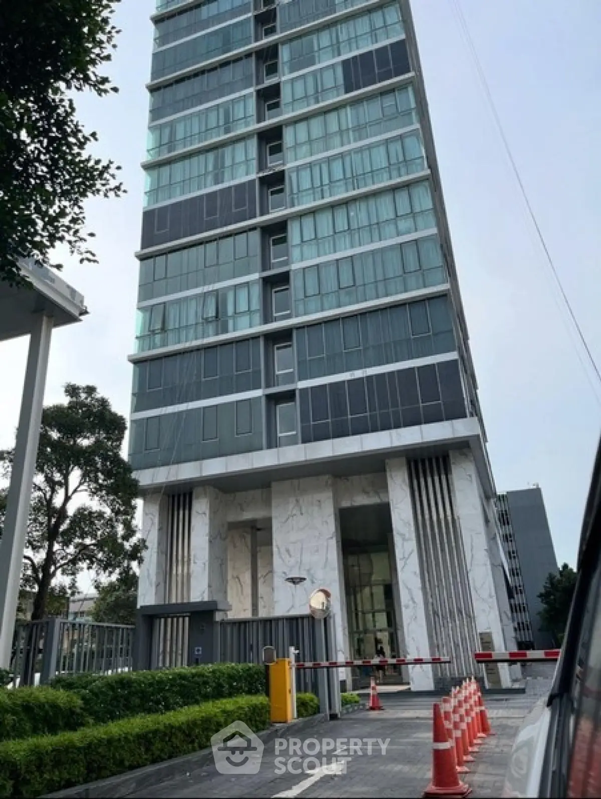 Modern high-rise building with sleek glass facade and secure entrance in urban setting.