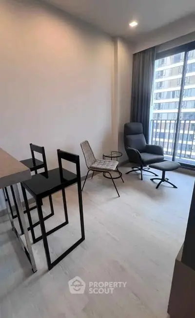 Modern living room with stylish furniture and large window offering city view.