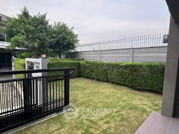 Charming garden area with lush greenery and secure fencing, perfect for outdoor relaxation.
