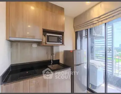 Modern kitchen with sleek cabinets, microwave, and fridge in a bright apartment with city view.