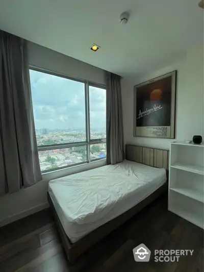 Cozy bedroom with large window offering stunning city view, perfect for relaxation and comfort.