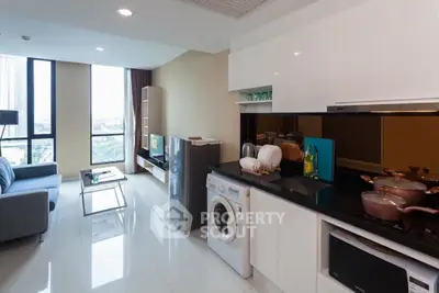 Modern open-plan living room with kitchen, featuring sleek appliances and large windows with city view.