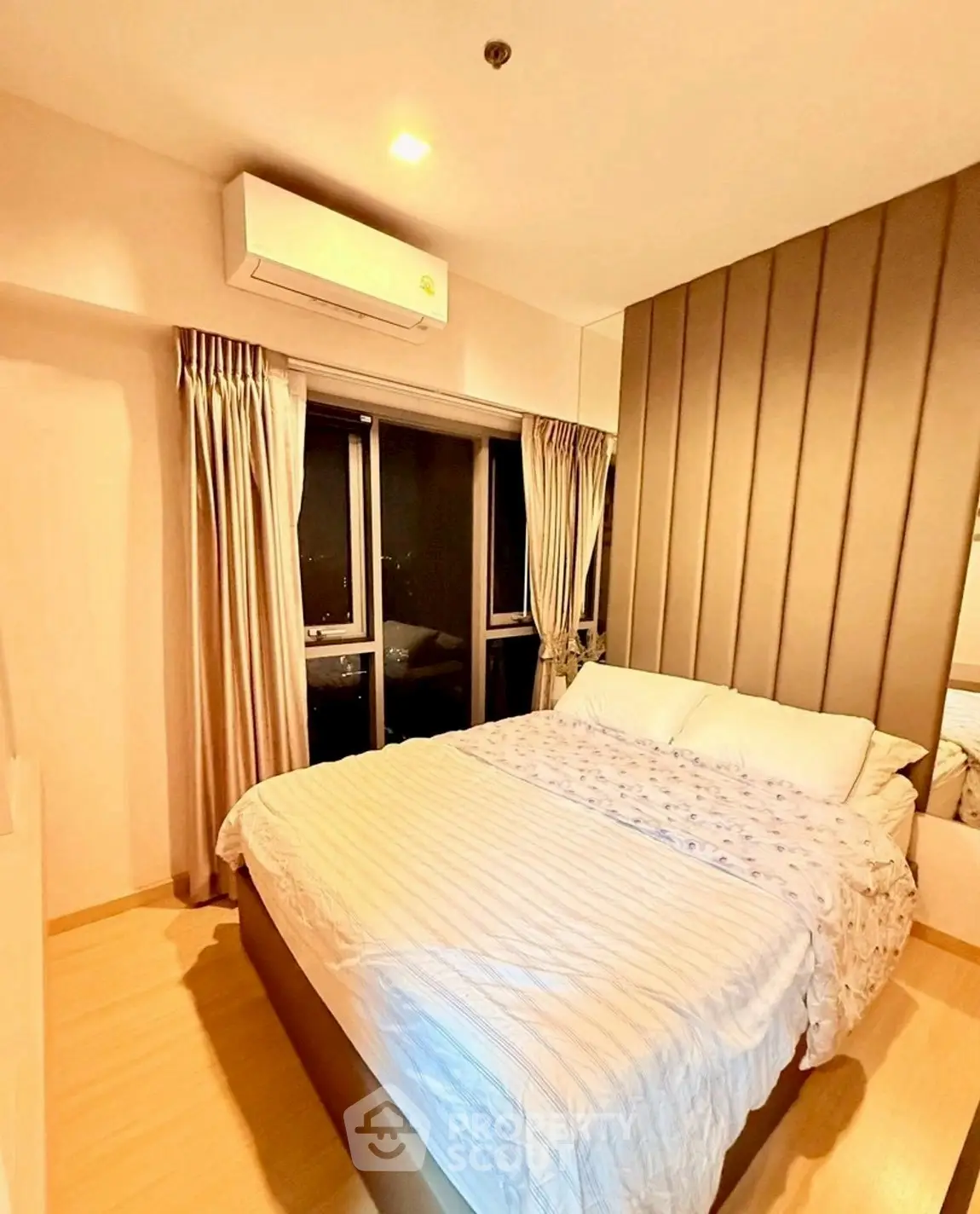 Cozy modern bedroom with stylish paneling and large window view.