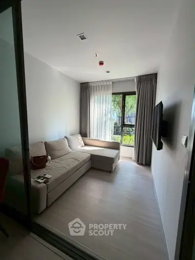 Cozy living room with modern sofa and natural light from large window.