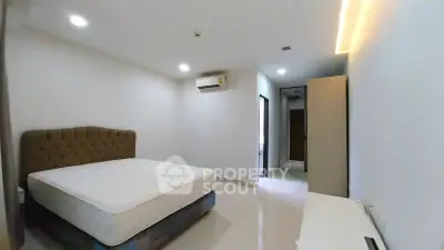 Spacious bedroom with modern design and ample natural light, featuring a comfortable bed and sleek furnishings.