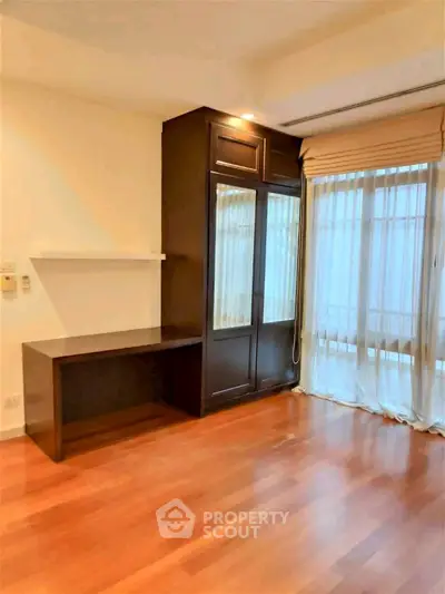 Spacious room with wooden flooring and large windows for natural light.
