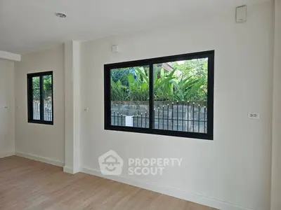 Spacious room with large windows offering a lush garden view, perfect for natural light and tranquility.