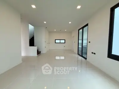 Spacious modern living room with sleek tile flooring and large windows.