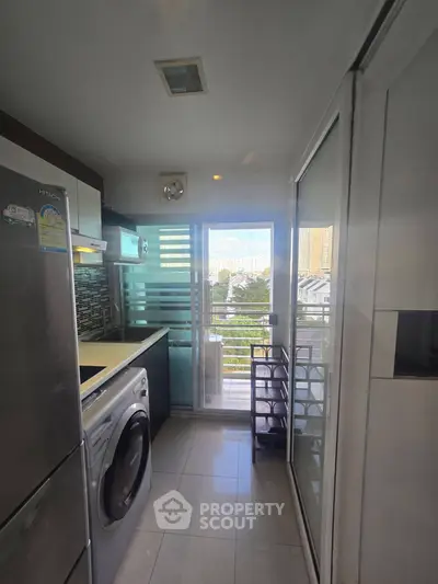 Modern kitchen with balcony view, featuring stainless steel appliances and sleek design.