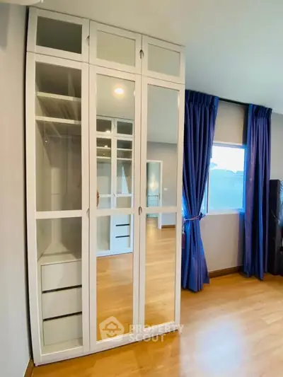 Spacious bedroom with mirrored wardrobe and large window for natural light