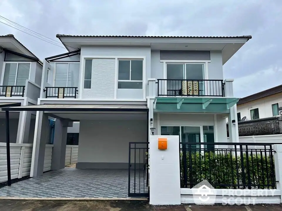 Modern two-story house with balcony and carport in a suburban neighborhood.