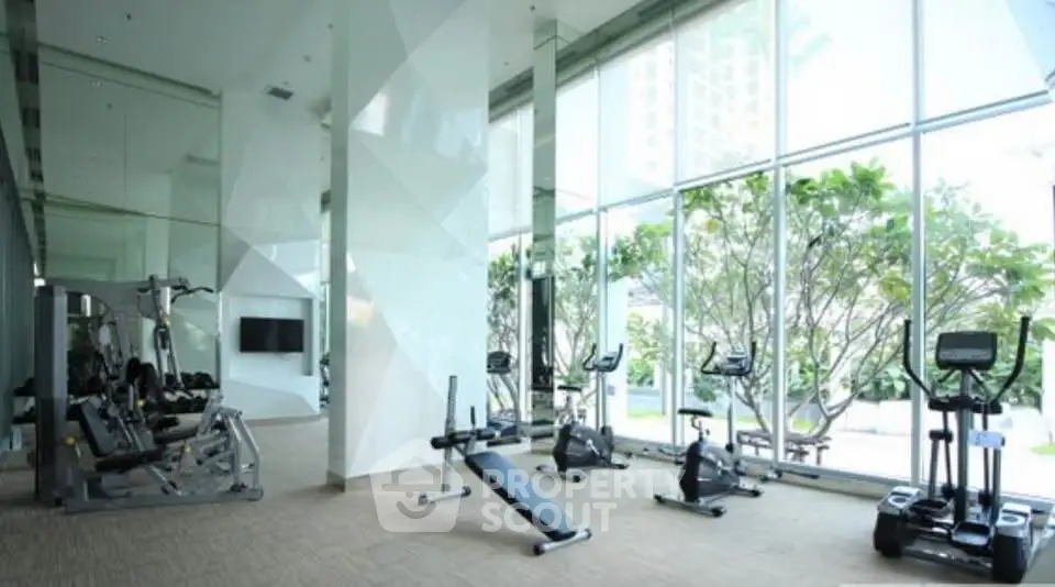 Luxurious gym with modern equipment and floor-to-ceiling windows offering a serene garden view.