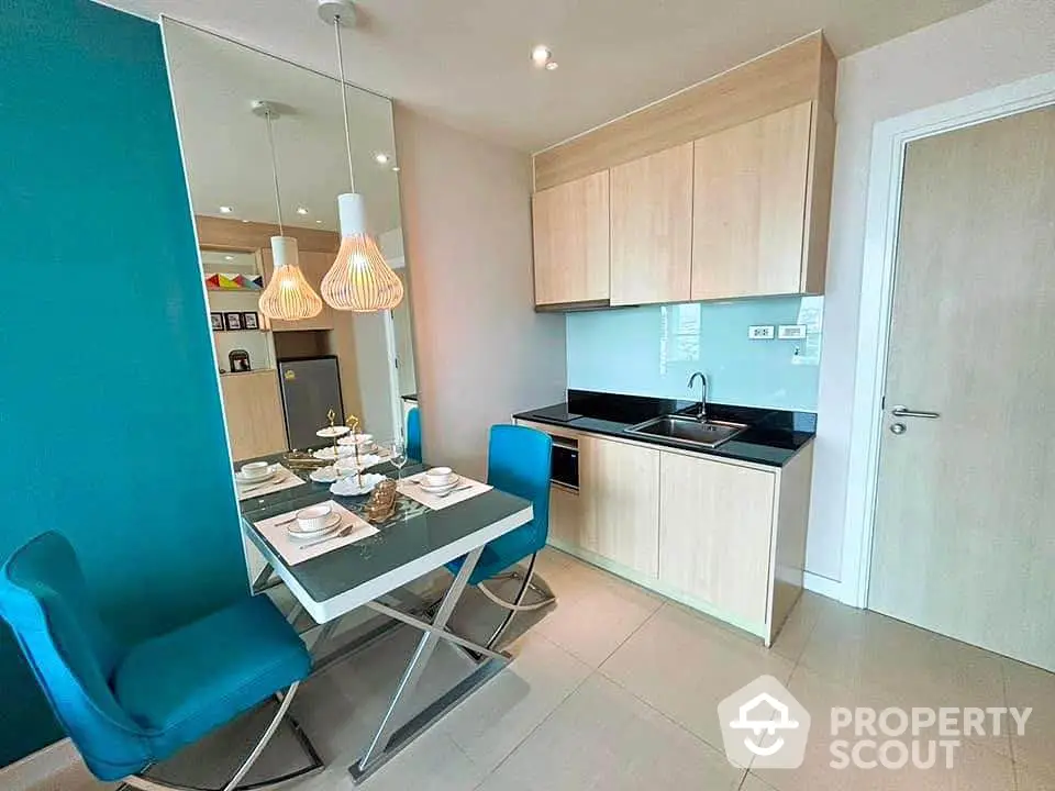 Modern kitchen with dining area featuring sleek cabinetry and stylish lighting in a cozy apartment.