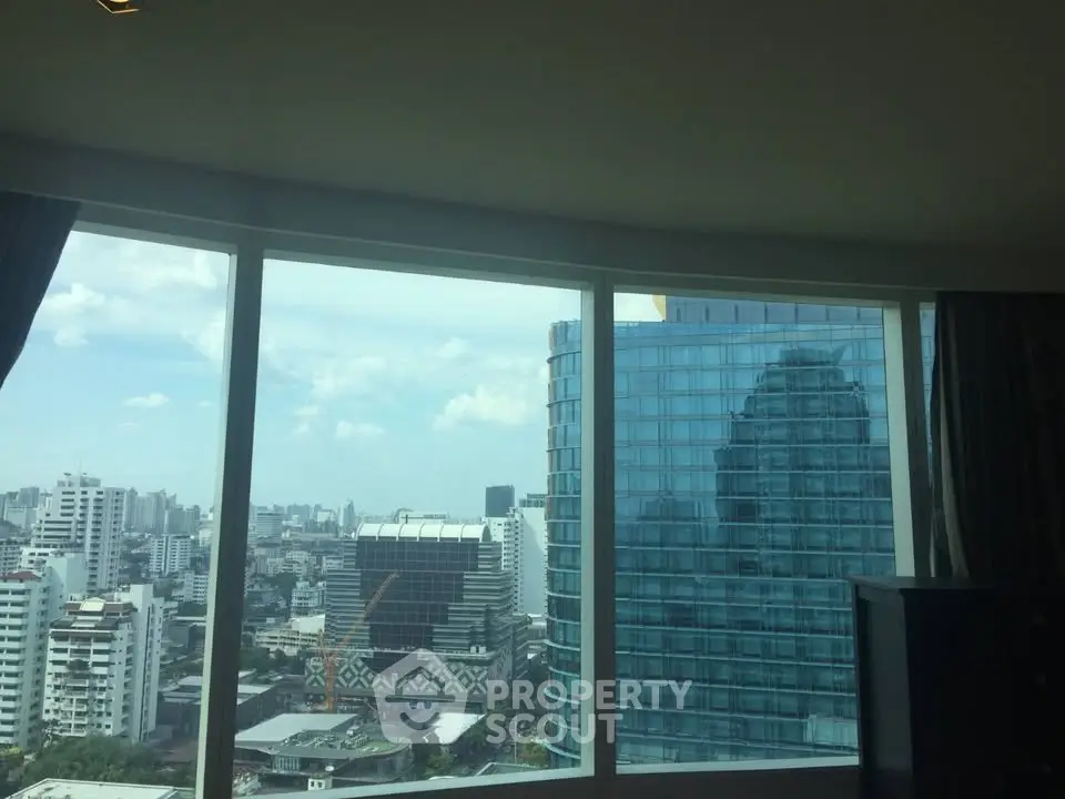 Stunning cityscape view from a high-rise apartment window, showcasing modern urban architecture.
