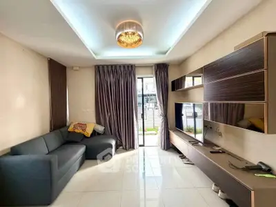 Modern living room with sleek furniture and large TV, featuring elegant lighting and floor-to-ceiling windows.