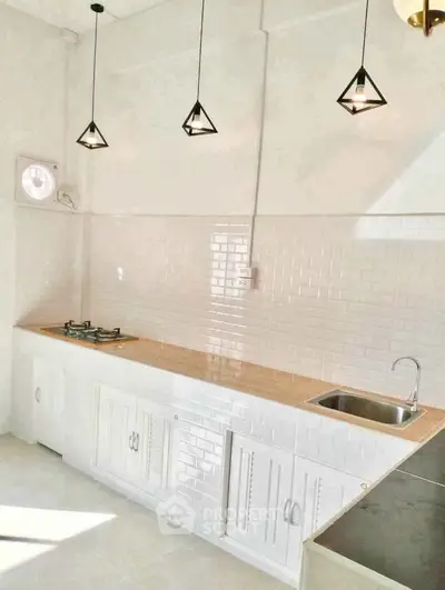 Modern kitchen with white cabinetry, gas stove, and stylish pendant lighting.
