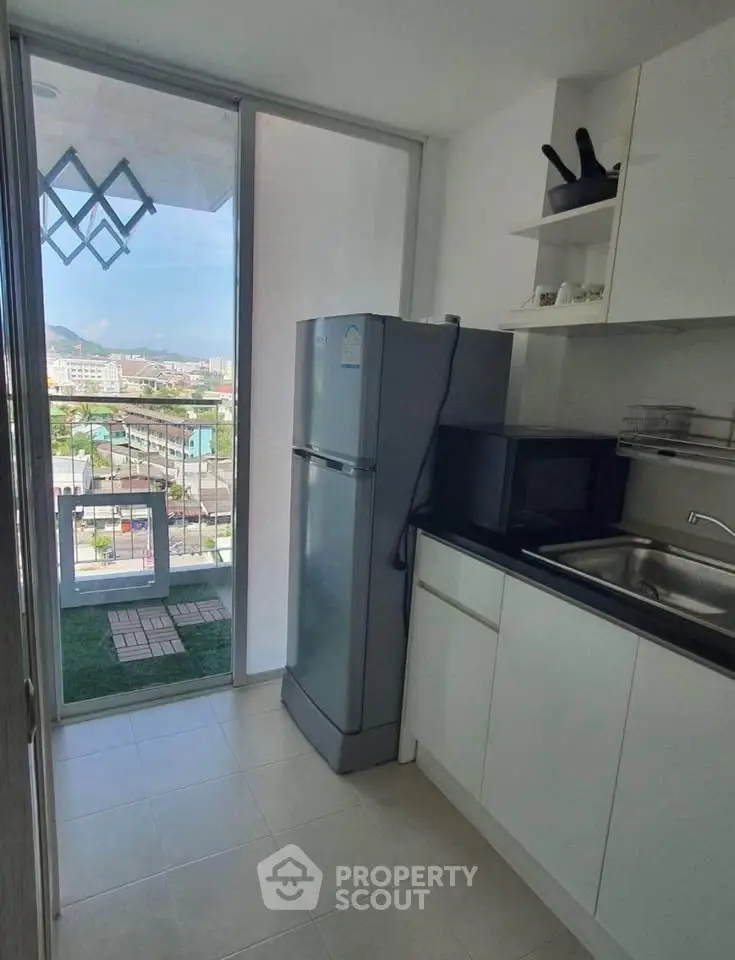 Modern kitchen with balcony view, featuring sleek appliances and ample storage in a high-rise apartment.