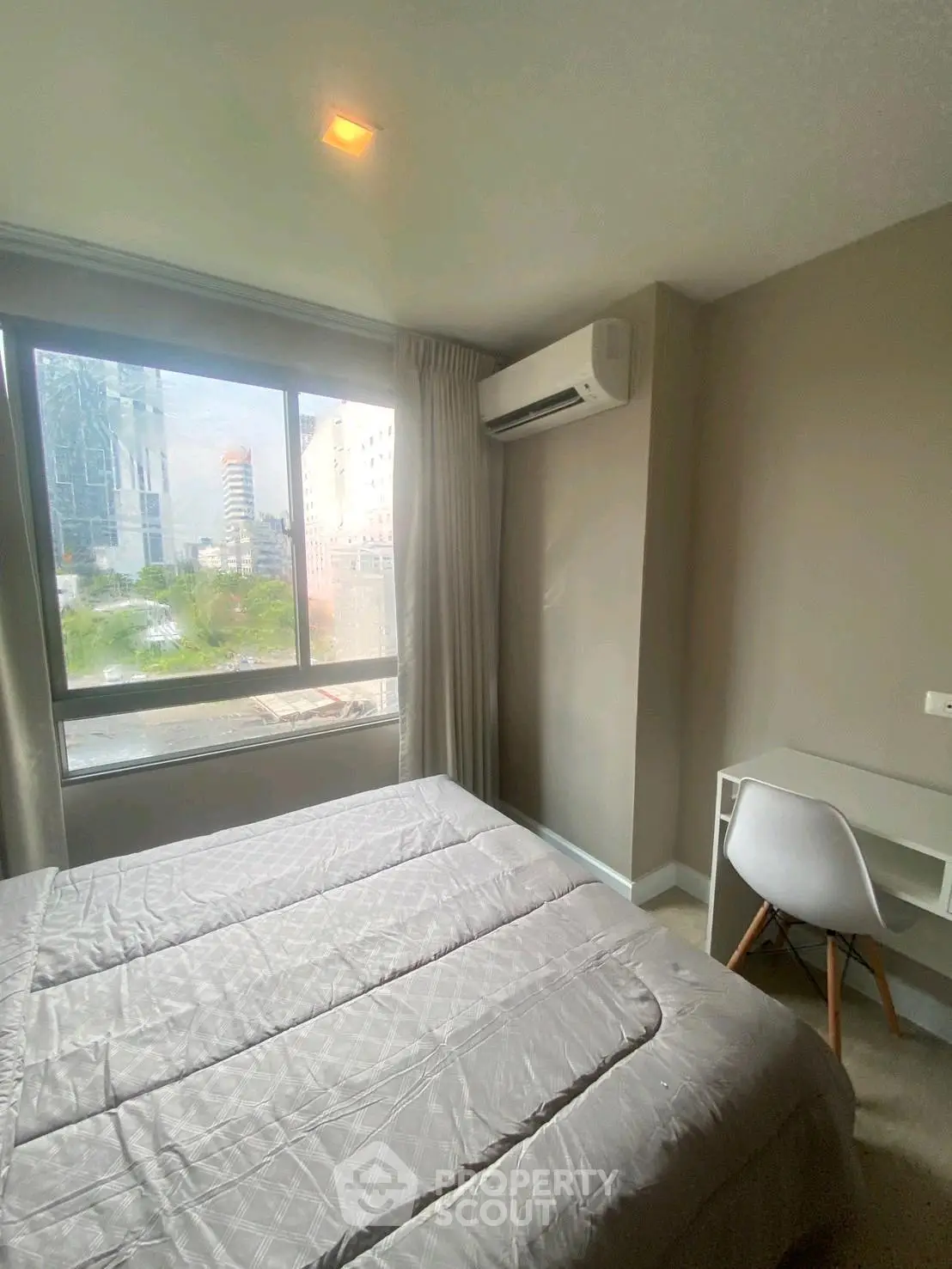 Cozy bedroom with large window and modern air conditioning unit, perfect for urban living.