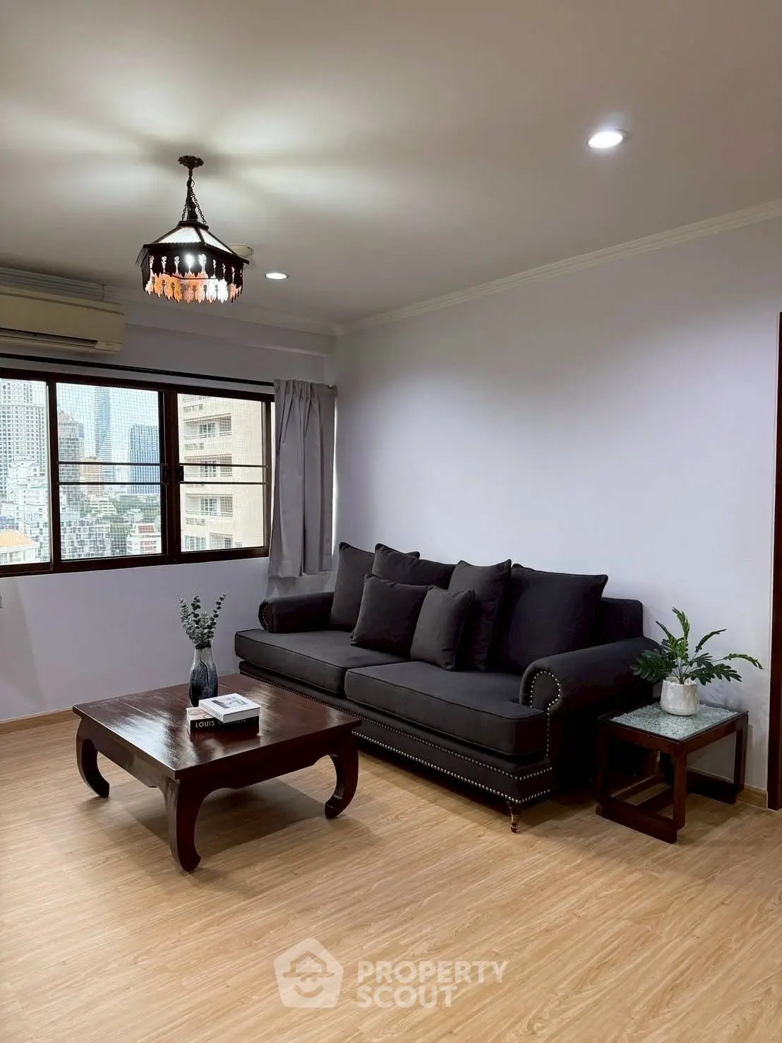 Stylish living room with modern black sofa and city view window.